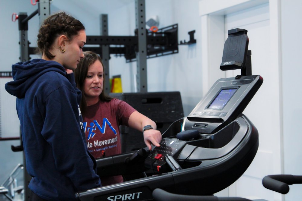 Trainer Bethany helping a client on the treadmill