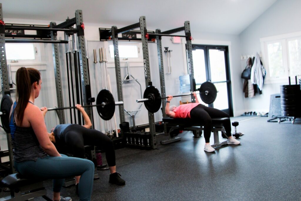 coach monitoring clients bench pressing weights